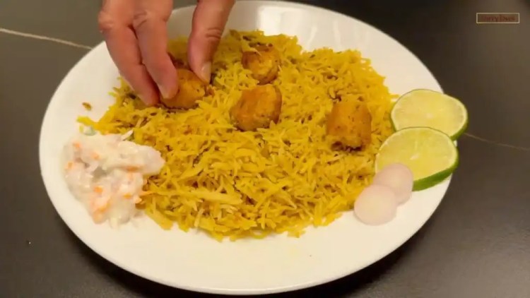fish kofta served on a plate with some raita, sliced onions and lemon wedges