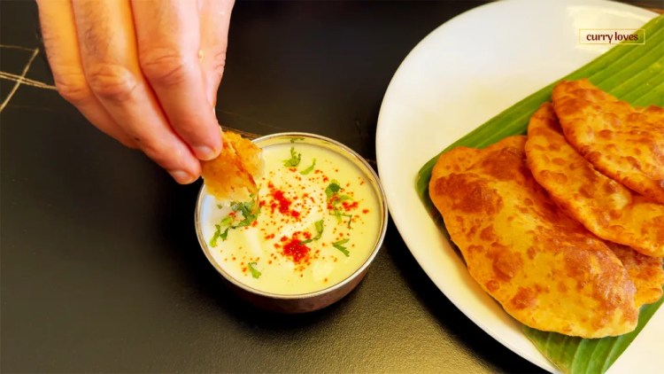 masala poori on a serving plate and dipped into a yogurt dip