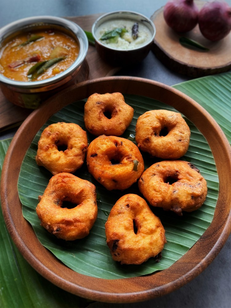 medu vadai on a serving plate with sambar and coconut chutney at the side