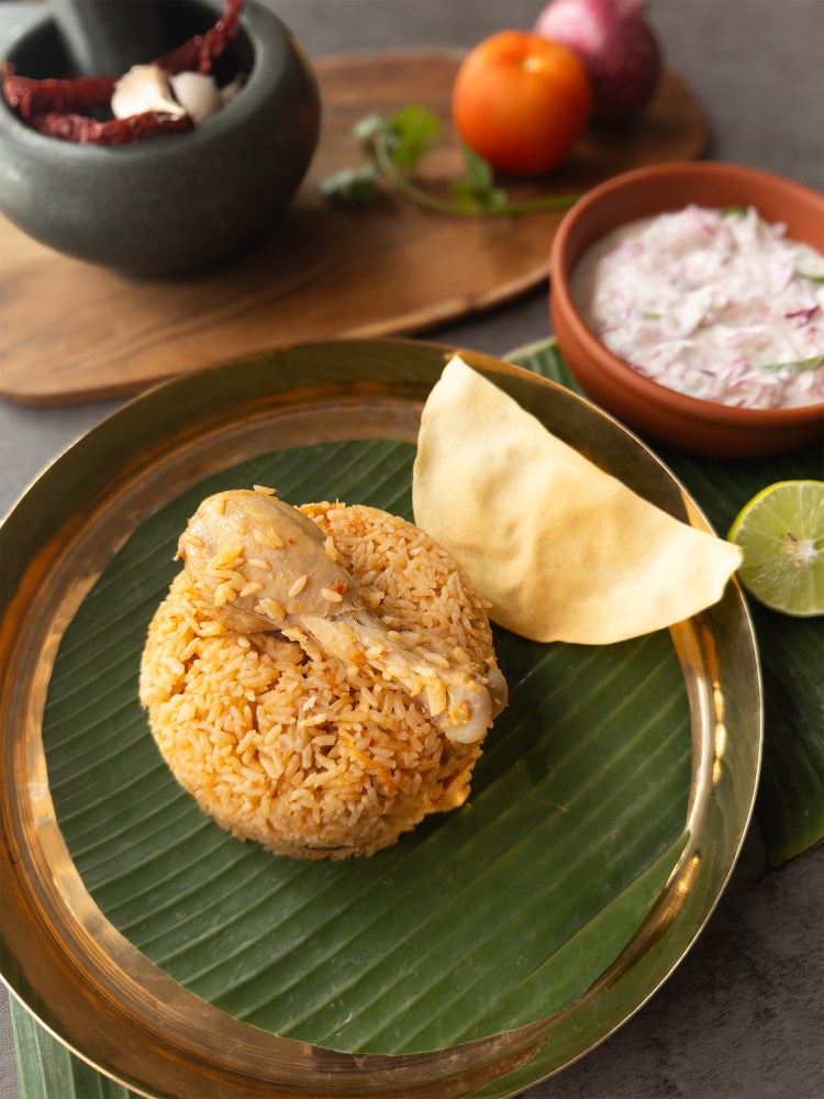 ambur chicken biryani on a serving plate with a pappadum and raita at the side