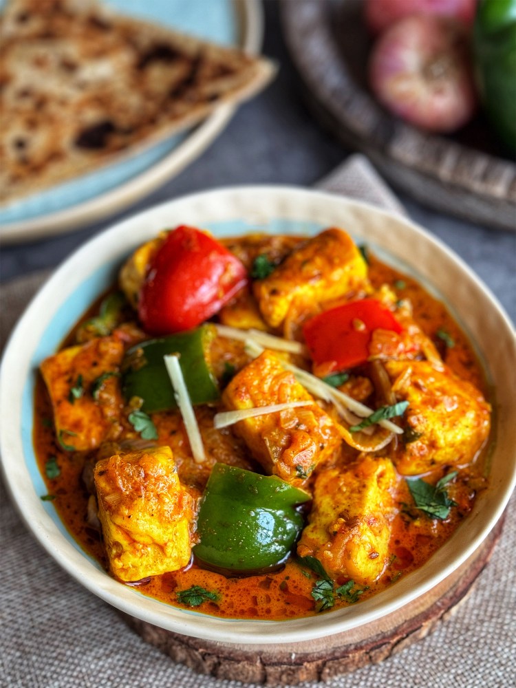 kadai paneer in a serving bowl with chapati at the side